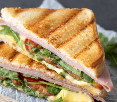 panini sandwich with ham cheese tomato arugula black slate background